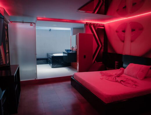 Estancia moderna con esquema rojo y negro, iluminada por neones rojos y decorada con arte gráfico sobre la cama; un motel que cuenta con jacuzzi.