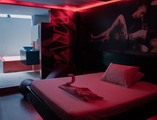 Rojo seductor ilumina la estancia monocromática con cama grande y arte mural en un motel con jacuzzi.